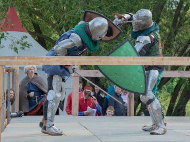 Tver / Rusya - 29 Eylül 2020: Ağır zırhlı savaşçılar kılıçlarla savaşıyor. Arka planda, hakem ve seyirciler. Ortaçağ Avrupa şövalye turnuvalarının tarihi yeniden yapılandırması