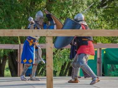 Orta Çağ zırhlı 60 santimlik savaşçılar arenada savaşıyor. Kılıçlarla donatılmış. Demir miğferler ve kalkanlar tarafından korunuyorlar. Ortaçağ Avrupa şövalye turnuvalarının tarihi yeniden yapılandırması
