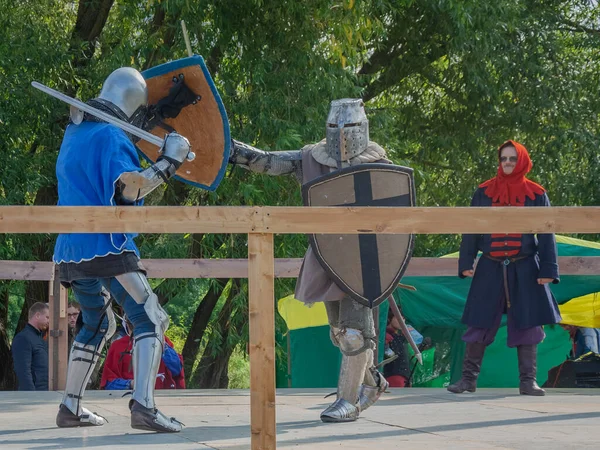 Tver / Rusya - 29 Eylül 2020: Ağır zırhlı savaşçılar kılıçlarla savaşıyor. Arka planda, hakem ve seyirciler. Ortaçağ Avrupa şövalye turnuvalarının tarihi yeniden yapılandırması
