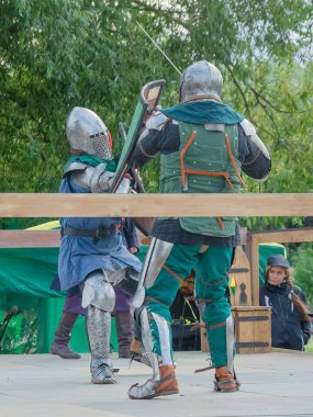 Tver / Rusya - 29 Eylül 2020: Ağır zırhlı savaşçılar kılıçlarla savaşıyor. Arka planda, hakem ve seyirciler. Ortaçağ Avrupa şövalye turnuvalarının tarihi yeniden yapılandırması