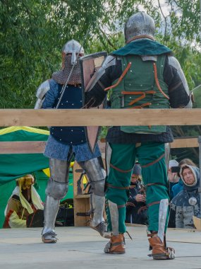 Tver / Rusya - 29 Eylül 2020: Ağır zırhlı savaşçılar kılıçlarla savaşıyor. Arka planda, hakem ve seyirciler. Ortaçağ Avrupa şövalye turnuvalarının tarihi yeniden yapılandırması