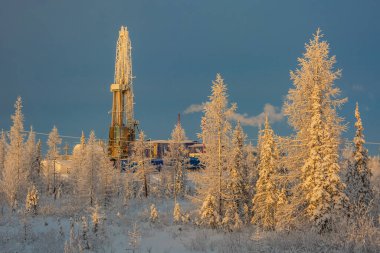 Kuzey tarlasında bir tayga ormanında sondaj sondajı. Kutup kışı gününde güneşin doğuşundaki manzara. Her yer karla kaplı. Yansıyan ışıkta sarı bir leke var.