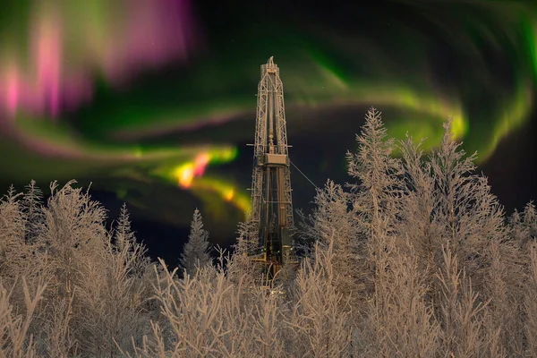 Polar night. Winter landscape with a drilling rig in the northern oil and gas field. In the background there is a beautiful sky with northern lights