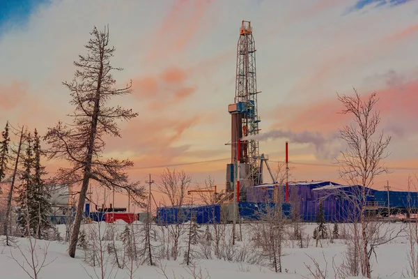 The landscape of the northern landscape of an oil and gas field with a drilling rig against the backdrop of a beautiful sky. Winter polar day