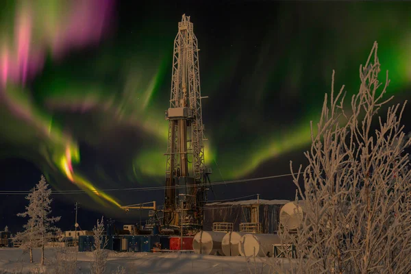 Polar night. Winter landscape with a drilling rig in the northern oil and gas field. In the background there is a beautiful sky with northern lights