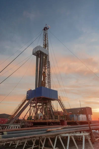 A site in the northern tundra at an oil and gas field. Drilling rig for drilling wells. Infrastructure and drilling equipment for drilling operations. Beautiful expressive sky