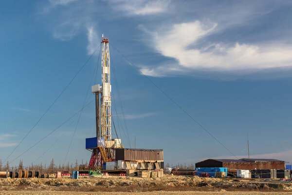 A site in the northern tundra at an oil and gas field. Drilling rig for drilling wells. Infrastructure and drilling equipment for drilling operations. Beautiful expressive sky