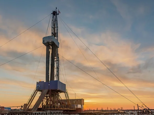 A site in the northern tundra at an oil and gas field. Drilling rig for drilling wells. Infrastructure and drilling equipment for drilling operations. Beautiful expressive sky