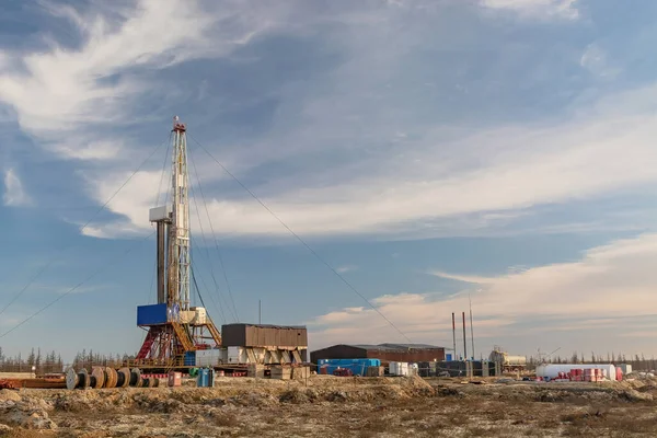 A site in the northern tundra at an oil and gas field. Drilling rig for drilling wells. Infrastructure and drilling equipment for drilling operations. Beautiful expressive sky