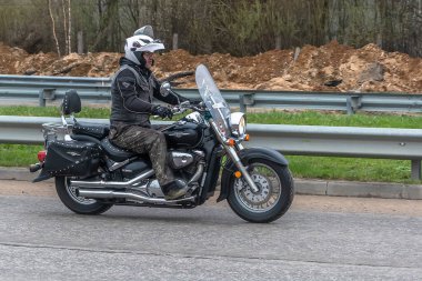 Tver Russia - 24 Nisan 2021: Miğferli ve teçhizatlı genç adam yolda motosiklet sürüyor. Bahar Bisiklet Festivali. Yaşam tarzı ve hobileri kavramı