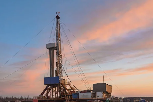 A site in the northern tundra at an oil and gas field. Drilling rig for drilling wells. Infrastructure and drilling equipment for drilling operations. Beautiful expressive sky