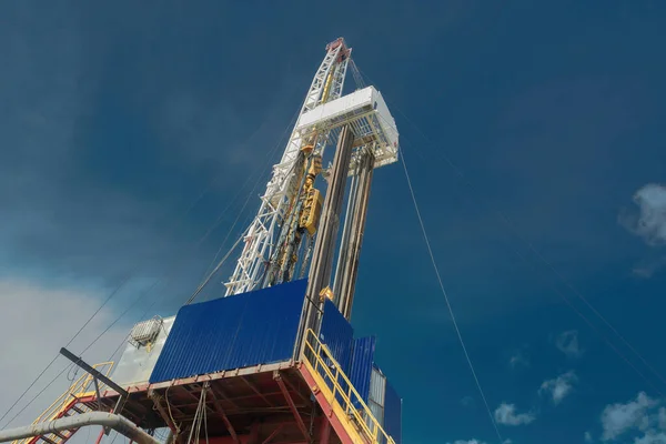 Petrol ve gaz kuyuları için sondaj kulesi. Genel detaylı görüş. Aşağıdan yukarıya doğru görüntüyü al. Güzel bir gökyüzünün arkaplanına karşı. Üste sondaj kulesi ve kuyuyu indirmek için borular.