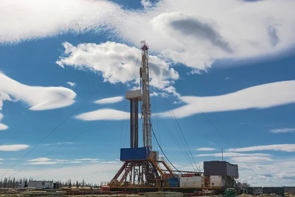 A site in the northern tundra at an oil and gas field. Drilling rig for drilling wells. Infrastructure and drilling equipment for drilling operations. Beautiful expressive sky