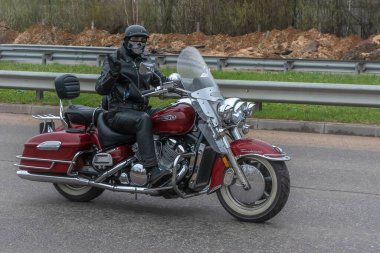 Tver Russia - 24 Nisan 2021: Miğferli ve teçhizatlı genç adam yolda motosiklet sürüyor. Bahar Bisiklet Festivali. Yaşam tarzı ve hobileri kavramı