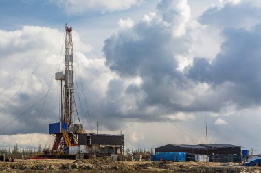 Kuzey petrol ve gaz sahasının doğal manzarası. Derin kuyular kazmak için sondaj kulesi var. Bahar kozalaklı orman, mavi bulutlu gökyüzü