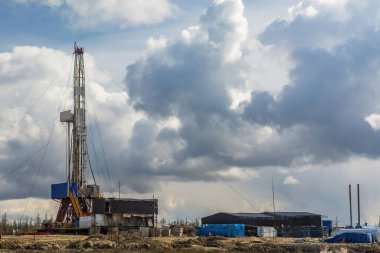 Kuzey petrol ve gaz sahasının doğal manzarası. Derin kuyular kazmak için sondaj kulesi var. Bahar kozalaklı orman, mavi bulutlu gökyüzü