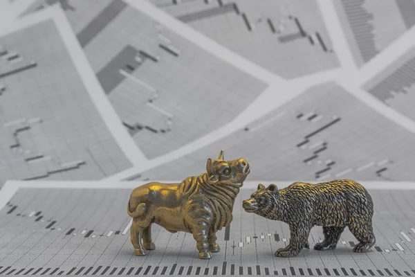 Metallic yellow bull and bear figures on the background of stock price charts. Exchange trade symbols. The concept of the struggle between buyers and sellers in the currency and securities market