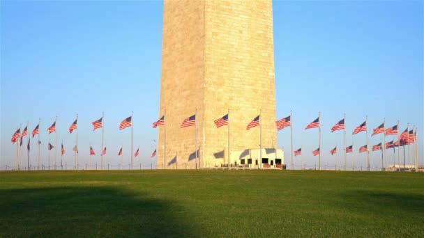 Bandeiras dos Estados Unidos perto do monumento de Washington acenando sobre o céu azul — Vídeo de Stock