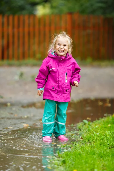 Happy little girl plays in a puddle — Stok fotoğraf