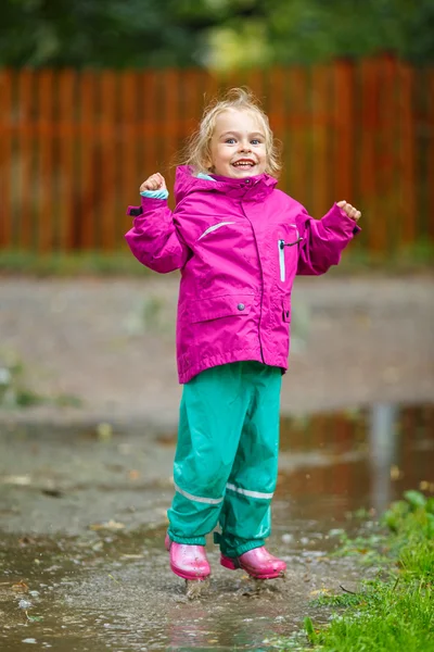 Happy little girl plays in a puddle — Stok fotoğraf