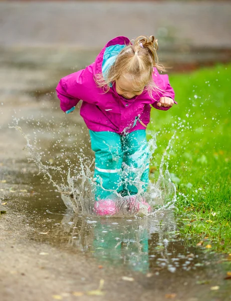 Happy little girl plays in a puddle — Stock Photo, Image