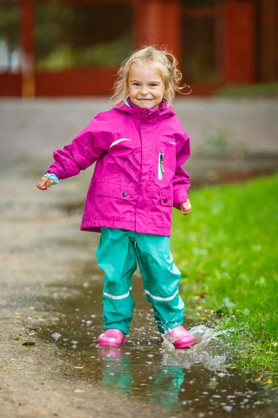 Happy little girl plays in a puddle — Stok fotoğraf