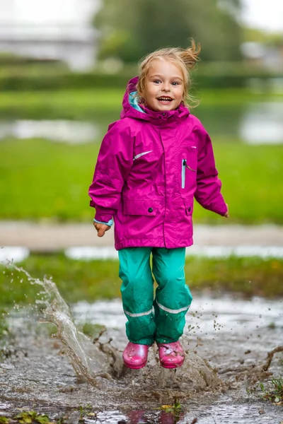 Happy little girl plays in a puddle — Stock Photo, Image