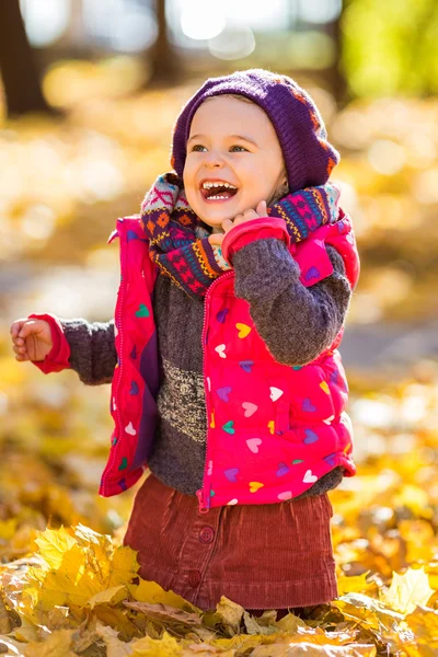 Glad liten flicka som leker i parken hösten — Stockfoto