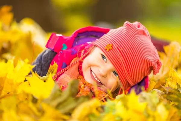 Menina brincando com folhas de outono — Fotografia de Stock