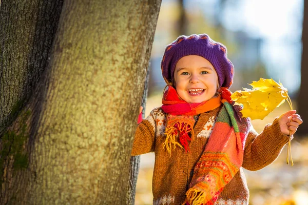 Fröhliches kleines Mädchen spielt im Herbstpark — Stockfoto