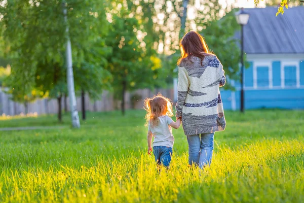 Mãe e filha caminhando no parque ensolarado — Fotografia de Stock