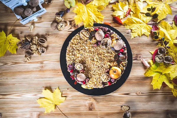 Çikolata soslu ev yapımı fındıklı kek ve ahşap sonbahar mahsulü masada ceviz ve elma.