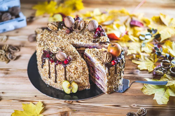 Sweet homemade nuts cake with chocolate topping and walnut nuts and apple on wooden autumn vintage table Tasty unhealthy dessert Front view