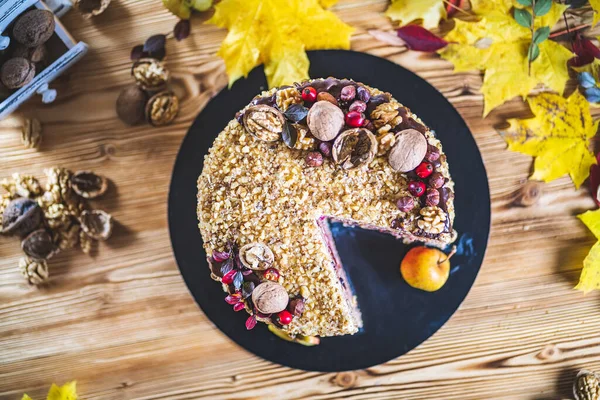 Çikolata soslu ev yapımı fındıklı kek ve ceviz fıstığı ahşap sonbahar mahsulü masada elma yer.