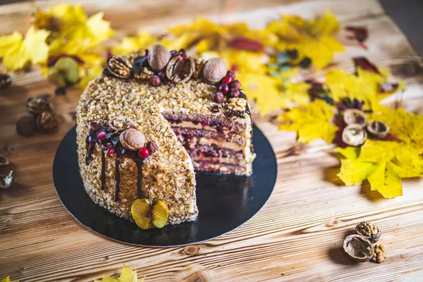 Çikolata soslu ev yapımı fındıklı kek ve ahşap sonbahar mahsulü masada ceviz ve elma.