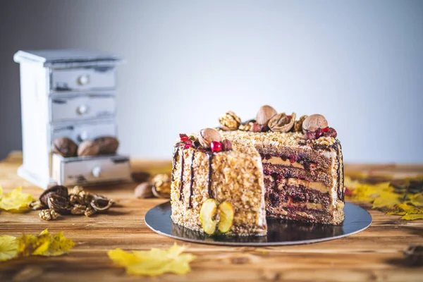 Sweet homemade nuts cake with chocolate topping and walnut nuts and apple on wooden autumn vintage table Tasty unhealthy dessert Front view