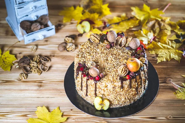 Çikolata soslu ev yapımı fındıklı kek ve ahşap şarap masasında ceviz ve elma. Sonbahar dekorasyonlu. Tatsız, sağlıksız tatlı manzaralı.