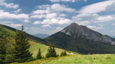 Güneşli yaz mevsiminde, mavi gökyüzünde beyaz bulutlarla dağlarda yürüyüş yapmak zaman kaybıdır.
