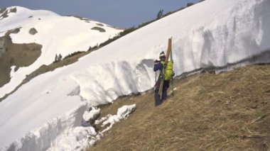 Genç kayakçı, güneşli kış mevsiminde karlı dağlarda çığ düşüşünün videosunu çekiyor.