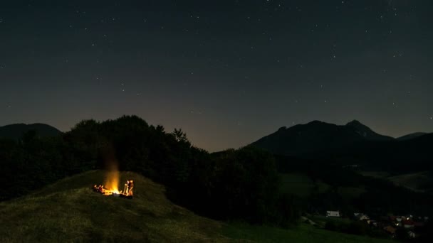 Un montón de amigos sentados alrededor de la fogata en el cielo estrellado con estrellas en la naturaleza de verano Time lapse — Vídeo de stock