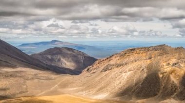 Gri bulutlar, Tongariro Parkı 'ndaki güneşli yaz gününde volkanik dağların üzerinde hareket ediyor. Zaman aşımı.