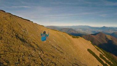 Güneşli bir akşamda rengarenk sonbahar dağları üzerinde nefes kesici yamaç paraşütü uçuşları. Huzurlu, adrenalinle dolu, serbest uçuş deneyimi ve kamera hareketleriyle nefes kesici hava manzarası..