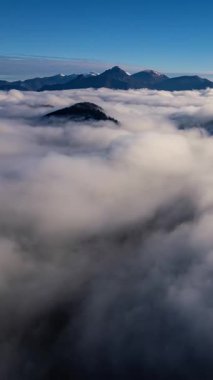 Güneşin doğuşunda sisli dağların dikey hava manzarası. Sis bulutları vadide huzur içinde akıyor. Huzurlu manzaranın zaman aşımı doğa ve seyahat projeleri için idealdir.