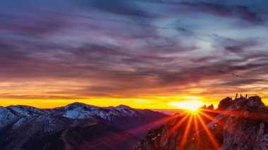 Panoramik zaman atlaması altın bir günbatımında karlı kış dağlarında canlı renkli bulutları yakalıyor. Sıcak ve huzurlu atmosferi olan çarpıcı dağlık doğa manzarası..