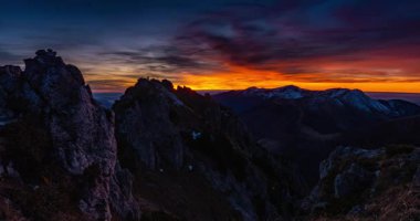 Alp dağları üzerinde canlı bir bahar gündoğumu gökyüzünün zaman atlaması. Altın güneş ışığı ve renkli bulutlar büyüleyici doğal bir zemin oluşturur. Yürüyüş, turizm ve açık hava maceraları için mükemmeldir..
