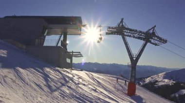 Güneşli bir günde teleferikli teleferikli Alpler kayak merkezinin panoramik manzarası. Tatil, kayak ve dağ manzaraları için mükemmel bir kış tatili sahnesi. 