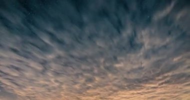 Yıldızlı bir gece gökyüzünde hızla ilerleyen bulutların akşam süreleri. Dinamik bir göksel sahne yıldızları, bulutları ve muazzam evreni güzel bir kozmik arka planda sergiliyor..