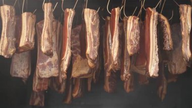 Aromatik odun dumanında sigara içen ev yapımı domuz pastırması. Geleneksel ev domuzu tedavisi, çiğ domuz eti üzerine yükselen otantik duman, lezzet ve doku açısından zengin..