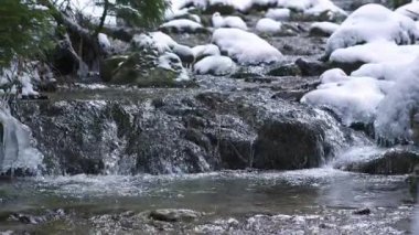 Donmuş kış doğasında akan bir dağ deresinin görüntüsü. Buzlu çağlayanlar ve kristal berrak su el değmemiş dağlık çevrede taze, soğuk ve huzurlu bir doğal manzara yaratır..