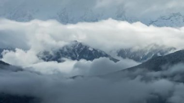 Fırtınalı bulutların, kışın Kafkasya Dağları 'nı sisli bir şekilde süpürmesi. Kar fırtınası koşulları dağcılık, yürüyüş ve kış turizmi için dramatik bir alp manzarası yaratıyor.